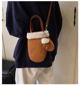 Detail of camel suede mitten bag with white shearling trim and plush pompom charm