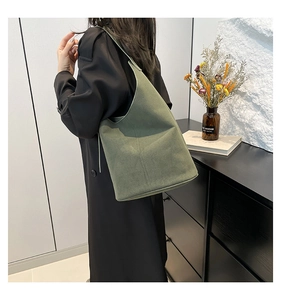 Close-up of green suede minimalist bucket bag showing large capacity and adjustable strap