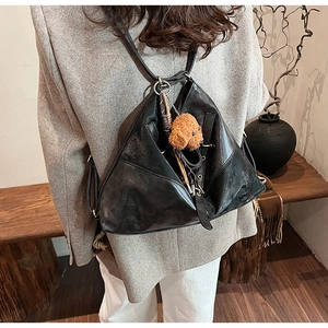 Détail d'un sac cabas noir triangulaire en cuir avec un charmant chien en peluche