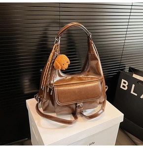 Close-up of brown vintage leather hobo bag with contrast stitching and teddy charm