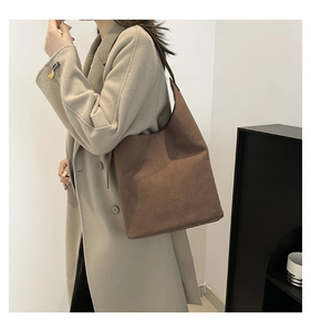 Deep brown suede hobo tote bag shown on shoulder in a minimalist indoor setting