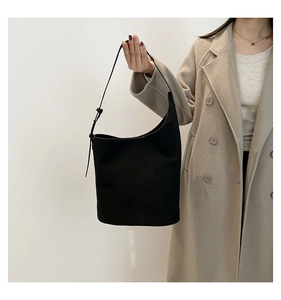 Detail of adjustable strap and matte leather texture on a black minimalist bucket bag