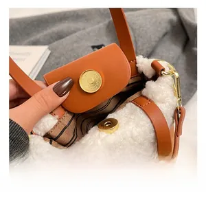 Detail of golden magnetic clasp on brown leather and white faux shearling handbag