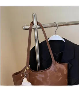 Close-up of brown patent leather tote bag with sturdy handles and plush charm detail
