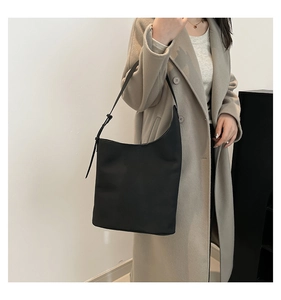 Close-up of a minimalist black crescent shoulder bag with adjustable leather strap