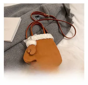 Detail of glove-shaped brown suede crossbody bag with white faux fur trim and strap