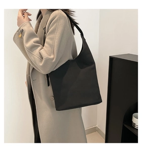 Side view of a large black minimalist shoulder tote bag with adjustable strap on a model