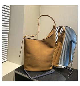 Detail of tan suede bucket bag showing vertical double stitching and asymmetric design