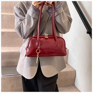 Close-up of red patent leather Boston bag with gold metallic lock and logo detail