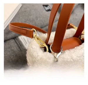 Detail of premium golden metal hook and leather strap on a brown suede shoulder bag