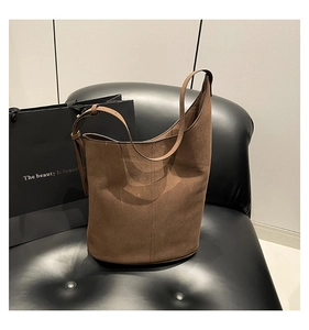 Close-up of brown suede bucket bag featuring vertical stitching and adjustable strap