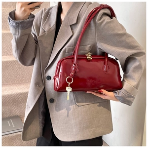 Detail of vintage dark red patent leather handbag with gold hardware and logo