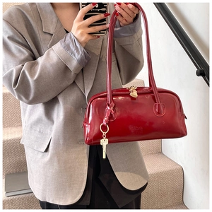 Detail of a red patent leather bowling bag with glossy finish and gold key charm