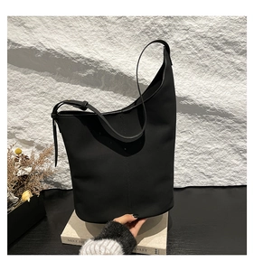 Minimalist black leather bucket bag detail with vertical seams and adjustable strap