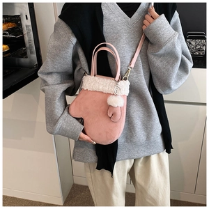 Detailed macro view of a pink suede crossbody bag with soft white faux fur trim and gold clasp