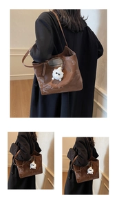 Detail view of brown leather tote bag interior lining and plush monster charm accessory