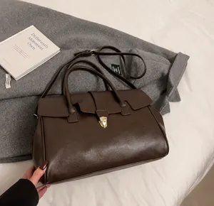 Detalle de bolso tote de cuero marrón vintage con cierre dorado y correa ajustable