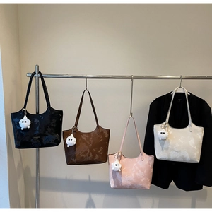 Close-up of stylish tote bags with marble texture and plush charms in various colors