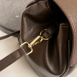 Detalle de bolso tote de cuero marrón oscuro con gancho de metal dorado pulido y anilla