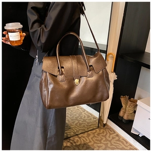 Vista detallada del elegante bolso tote de cuero marrón con cierre metálico para mujer.