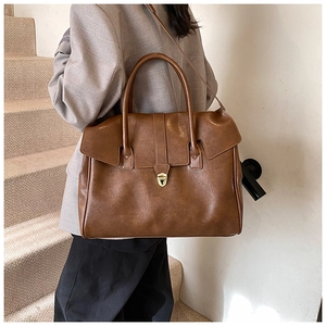 Detalle de bolso tote marrón vintage con cierre metálico y asas dobles