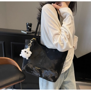 Detail of black leather tote bag with a golden logo and a cute white sheep charm