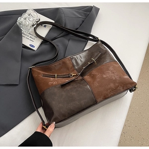 Détail du sac rétro bicolore en cuir mat avec boucle décorative et bandoulière