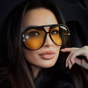 Modern aviator sunglasses with black frame and orange gradient lenses on model