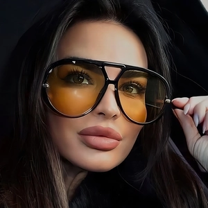 Detailed close-up of large black aviator sunglasses with orange gradient lenses on model