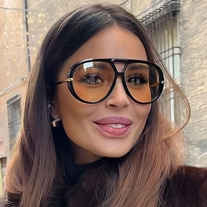 Chic female model wearing oversized aviator sunglasses with retro orange tinted lenses