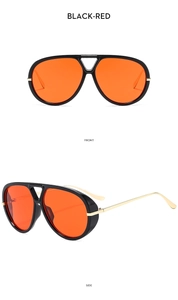 Detail of oversized black pilot sunglasses with orange lenses and gold metal temples