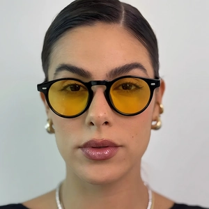 Frontansicht einer runden schwarzen Retro-Sonnenbrille mit gelben Gläsern am Modell