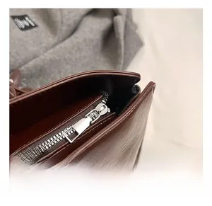 Close-up of premium dark brown leather handbag featuring silver metal zipper and hardware