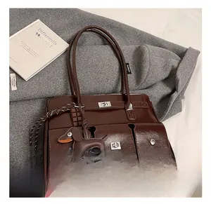 Detail of dark brown glossy tote bag featuring three front pockets and a dachshund charm