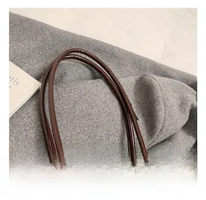 Close-up of shiny dark brown faux leather handbag with silver twist lock and round handles