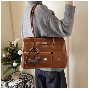 Detail of a brown vintage leather tote with multiple functional pockets and dog charm