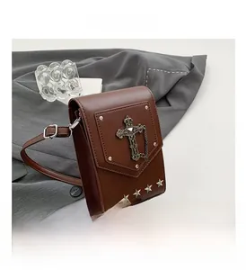 Detail of vintage brown crossbody bag with metal cross pendant and star rivets