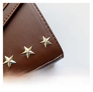 Detail of dark brown leather texture with silver star rivets and premium stitching