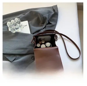 Internal storage view of brown vintage rivet crossbody bag showing phone and lipstick