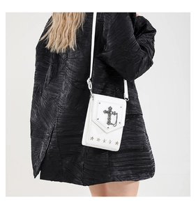 White leather crossbody bag with silver cross and star studs worn by a model in black