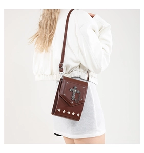 Detail of dark brown leather crossbody bag with vintage metal cross and star rivets