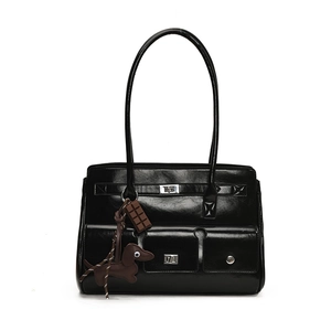 Close-up of black glossy handbag with multi-pockets, metal buckles and cute charms