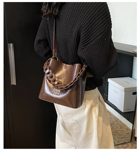 Détail du sac seau en cuir ciré vintage avec bandoulière chaîne et logo en métal