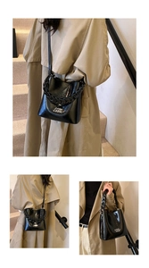 Détail du sac seau en cuir ciré noir avec chaîne épaisse et logo de la marque