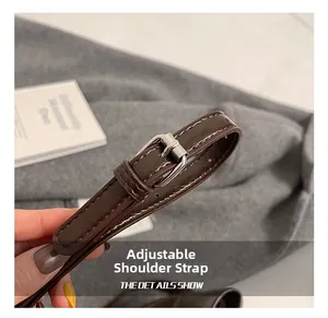 Détail de la bandoulière réglable sur sac en cuir marron avec boucle argentée