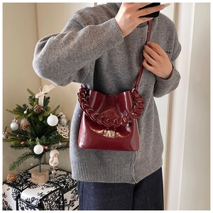 Détail du sac seau en cuir verni rouge foncé avec bandoulière chaîne et décor de Noël