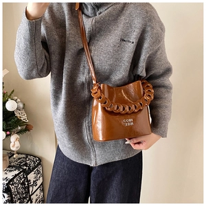 Détail d'un sac seau en cuir marron brillant avec lettrage argenté et bandoulière chaîne