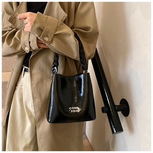 Détail du sac seau noir brillant avec texte imprimé et bandoulière en chaîne de résine