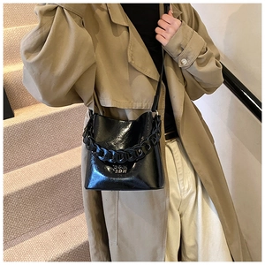 Vue détaillée du sac seau noir en cuir ciré avec une chaîne épaisse et une finition vernie