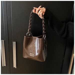 Détail du sac seau marron en cuir ciré vintage avec grosse chaîne et logo COIN 2DH